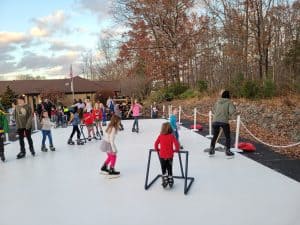 Families skating on a Jump Around VA portable ice rink at an outdoor event in Virginia