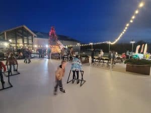 Kids skating on a Jump Around VA synthetic ice rink at an outdoor holiday event at night