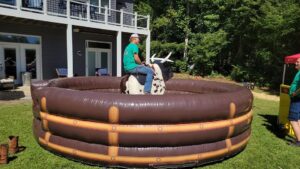 Mechanical bull attraction set up on an inflatable safety mat in a backyard for event rental.